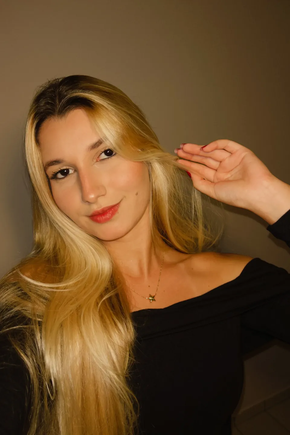 Retrato de Clara Fernandes, de blusa preta, com a mão no cabelo